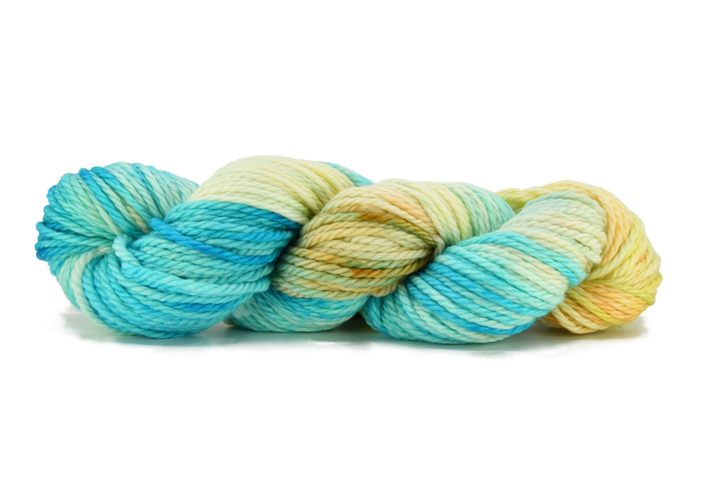 A twisted skein of Barn Yarn hand-dyed bulky weight yarn in colorway Down by the Seaside with breezy blues, sandy neutrals, and sea-glass greens, perfect  knitting and crochet.