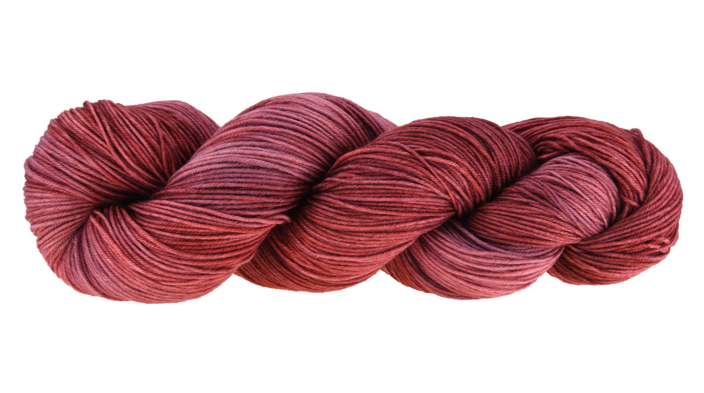 Wine Rose hand-dyed fingering yarn in a deep rose shade, shown in a twisted hank to emphasize its tonal richness and smooth texture.