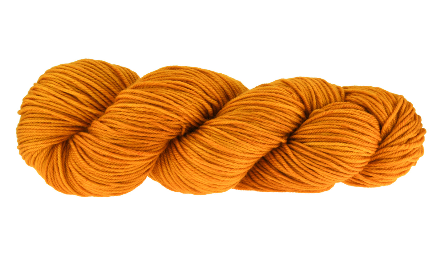 A twisted skein of Barn Yarn hand-dyed DK weight yarn in colorway Golden Era, a radiant golden yellow shade, perfect for warm and luxurious knitting and crochet projects.
