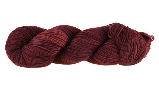 A twisted skein of Barn Yarn hand-dyed fingering weight yarn in colorway Chocolate Moose; a rich, earthy brown shade, perfect for warm and cozy knitting and crochet projects.