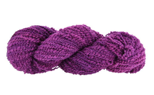 A twisted hank of Barn Yarn hand-dyed boucle yarn in colorway Grape-ly Appreciated showing vivid purple tones, ideal for eye-catching knitting and crochet creations.