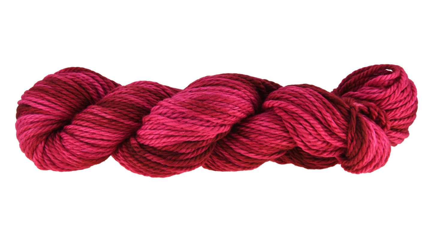 A twisted hank of bulky weight hand-dyed yarn in colorway Pomegranate featuring layered bright and dark saturated pink tones, ideal for vibrant handmade creations.