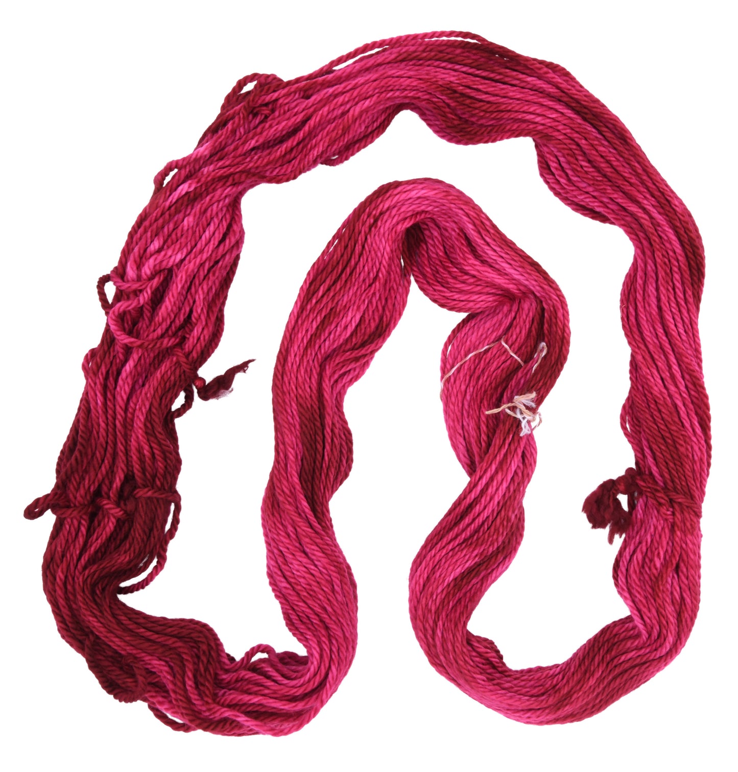 an unfolded hank of bulky weight hand-dyed yarn in colorway Pomegranate featuring layered bright and dark saturated pink tones, ideal for vibrant handmade creations.