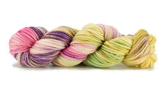 A twisted skein of Barn Yarn hand-dyed bulky weight yarn Bubble Bath, in soft blush pinks, airy whites, and lavender hints, perfect for delicate knitting and crochet projects.