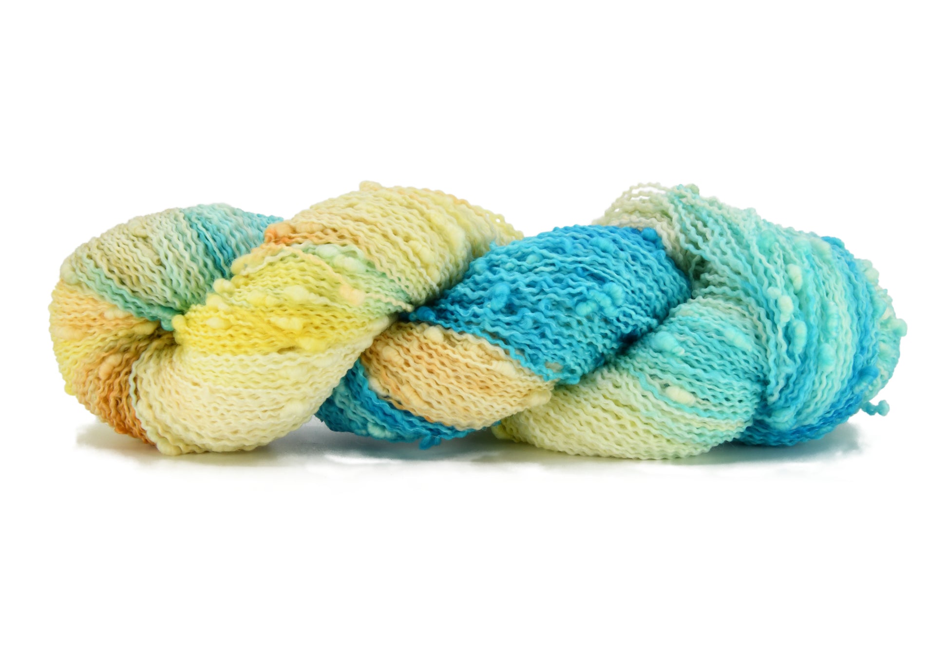 A twisted skein of Barn Yarn hand-dyed slub yarn in colorway Down by the Seaside with breezy blues, sandy neutrals, and sea-glass greens, perfect  knitting and crochet.