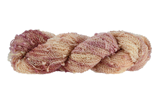 A twisted skein of Barn Yarn hand-dyed slub yarn in colorway Melrose Place featuring shades of mauve and cream perfect for glamorous knitting and crochet projects.