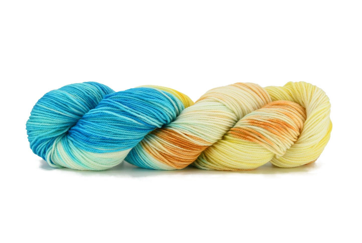 A twisted skein of Barn Yarn hand-dyed sport weight yarn in colorway Down by the Seaside with breezy blues, sandy neutrals, and sea-glass greens, perfect  knitting and crochet.