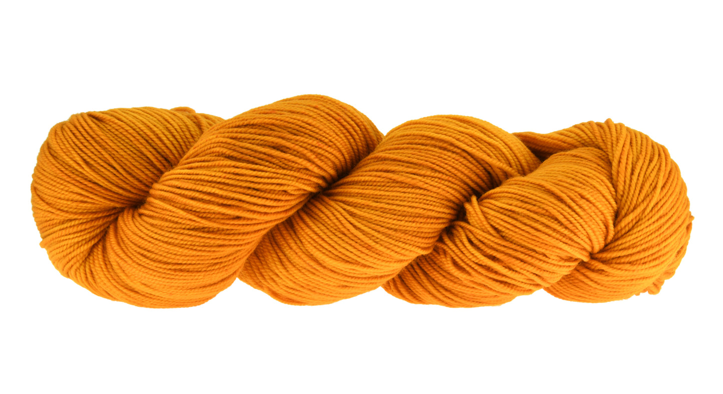 A twisted skein of Barn Yarn hand-dyed sport weight yarn in colorway Golden Era, a radiant golden yellow shade, perfect for warm and luxurious knitting and crochet projects.