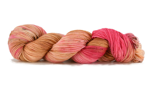 A twisted skein of Barn Yarn hand-dyed sport weight yarn in colorway Poolside Popsicle featuring bright strawberry pink, vanilla and chocolate sprinkles, perfect for  knitting and crochet projects.