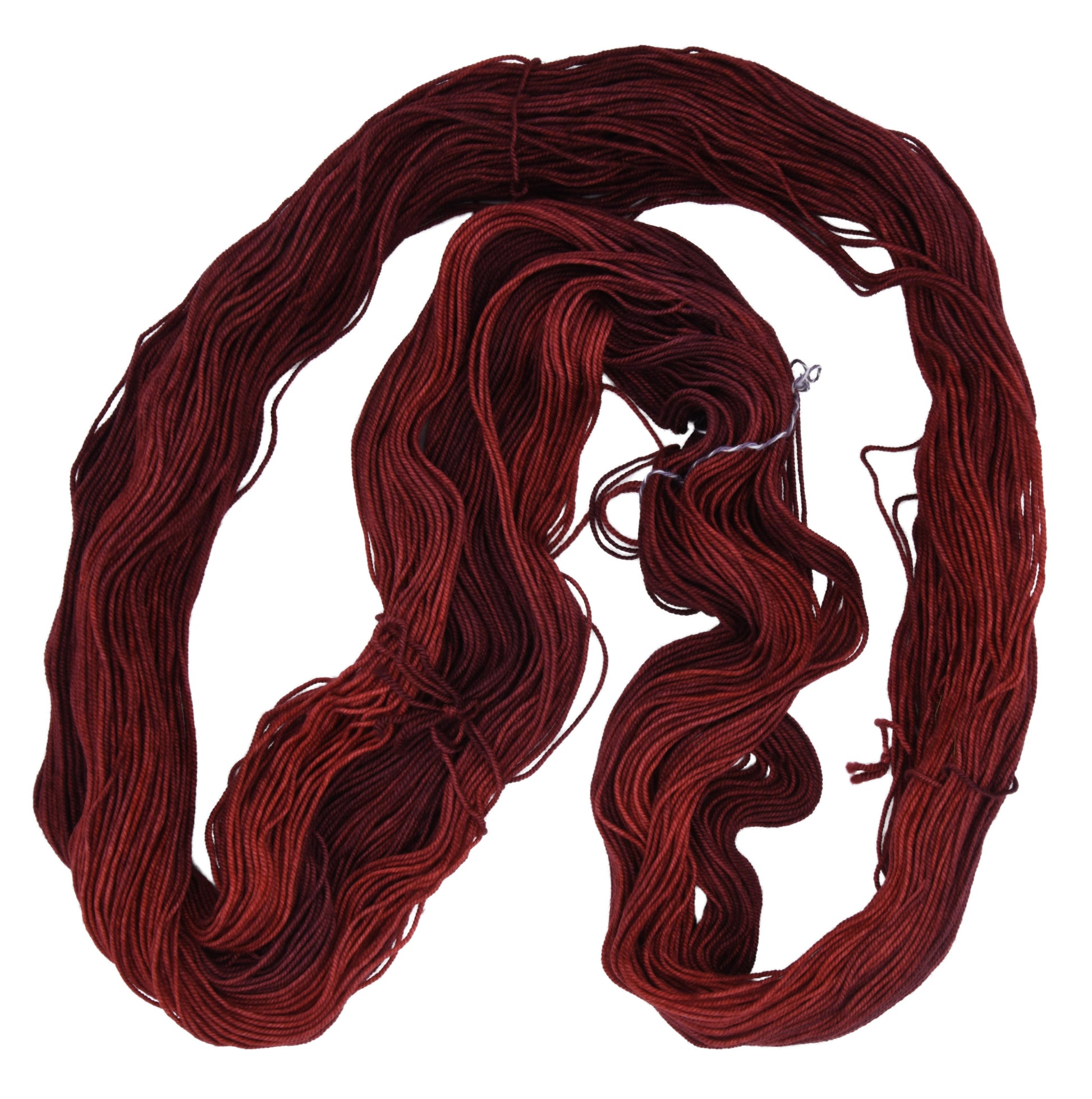 An unfolded skein of Barn Yarn hand-dyed sport weight yarn in colorway Chocolate Moose; a rich, earthy brown shade, perfect for warm and cozy knitting and crochet projects.