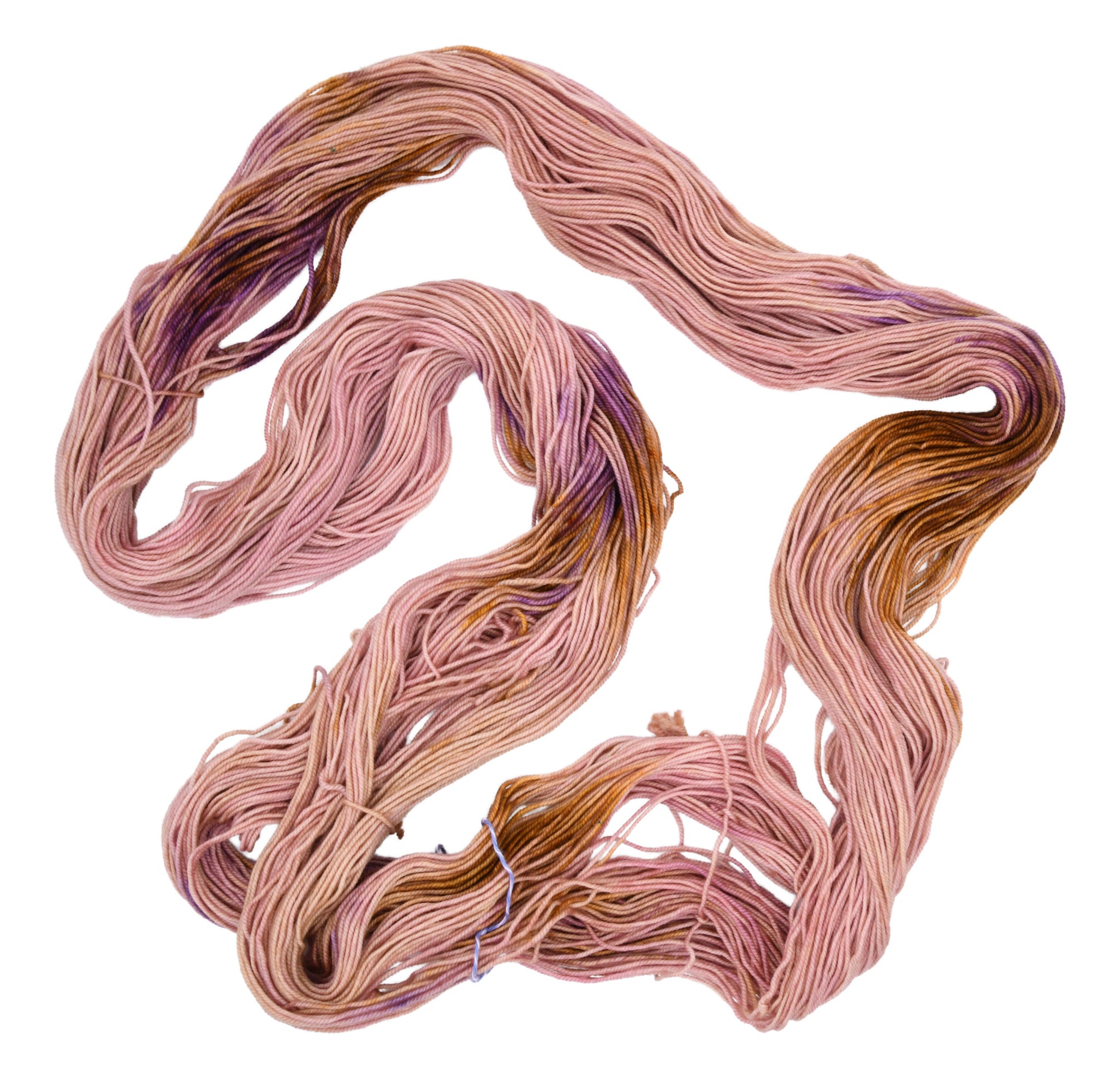 An unfolded skein of Barn Yarn hand-dyed sport weight yarn in colorway Nougat, a light pink, toffee, and purple combination, perfect for knitting and crochet projects.