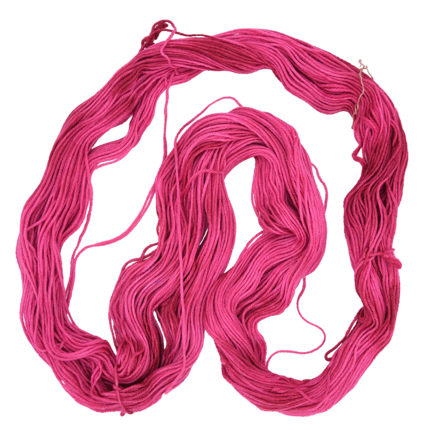 An unfolded hank of worsetd weight hand-dyed yarn in colorway Pomegranate featuring layered bright and dark saturated pink tones, ideal for vibrant handmade creations.