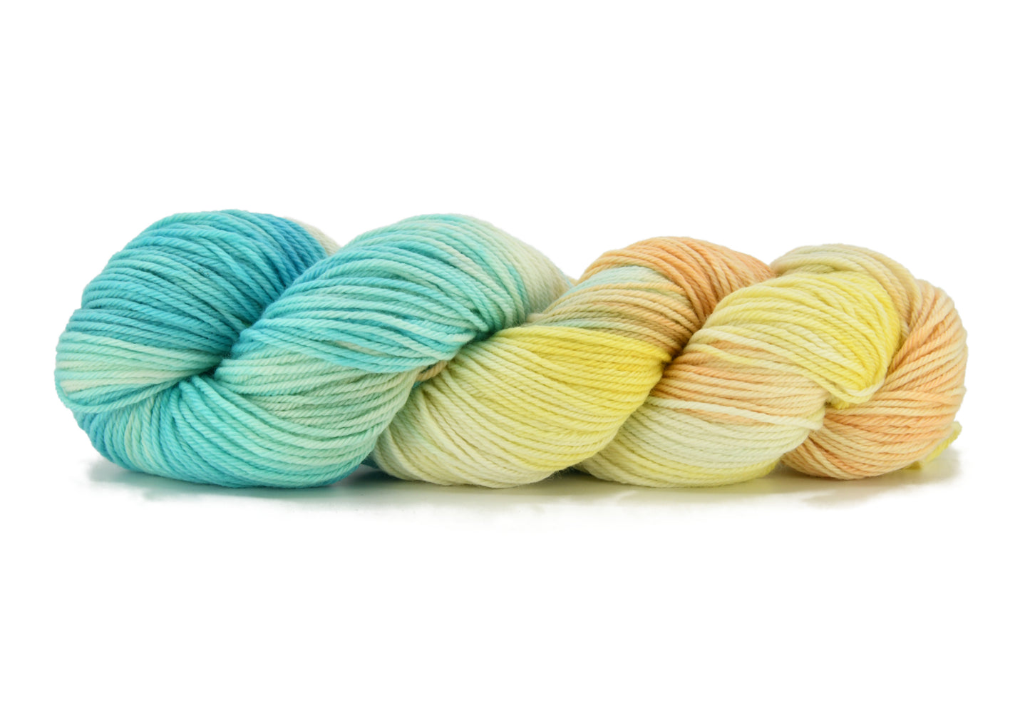 A twisted skein of Barn Yarn hand-dyed worsted weight yarn in colorway Down by the Seaside with breezy blues, sandy neutrals, and sea-glass greens, perfect  knitting and crochet.