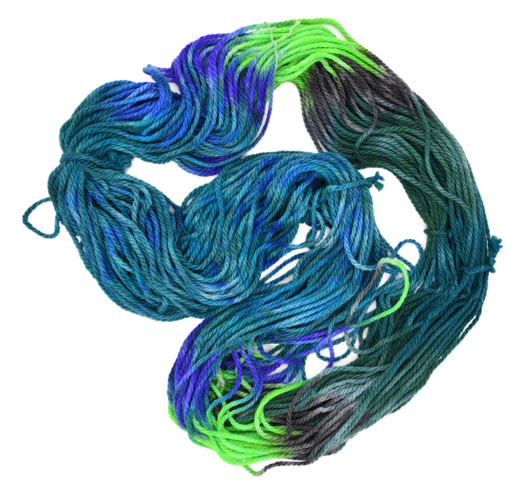 An unfolded skein of Barn Yarn hand-dyed bulky weight yarn in colorway Play the Peacock -vibrant teal, emerald green, rich blue inspired by the colors of a peacock’s feathers.